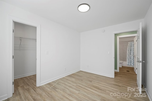 unfurnished bedroom with a walk in closet, a closet, and light wood-type flooring