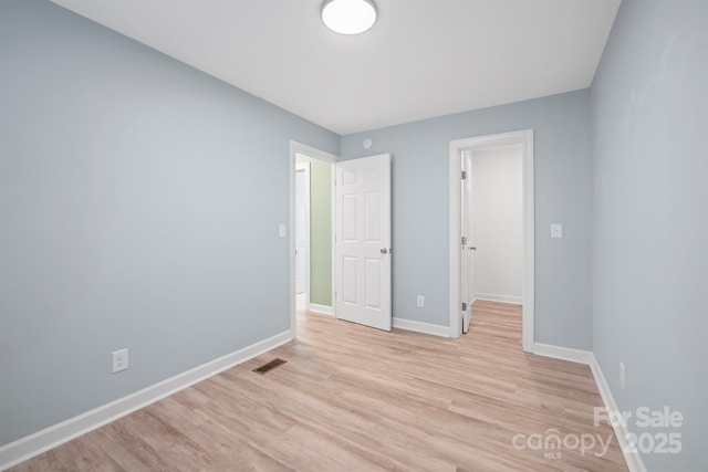 unfurnished bedroom featuring a spacious closet, a closet, and light wood-type flooring