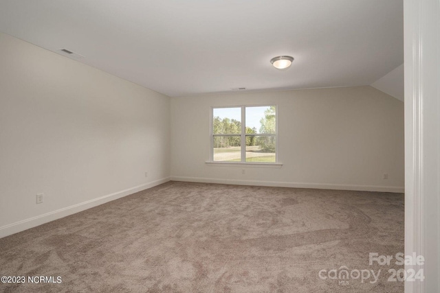 empty room featuring carpet and lofted ceiling