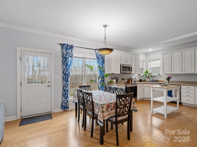 dining space with crown molding and light hardwood / wood-style floors