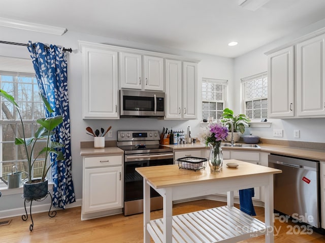 kitchen featuring white cabinetry, sink, light wood-type flooring, and appliances with stainless steel finishes