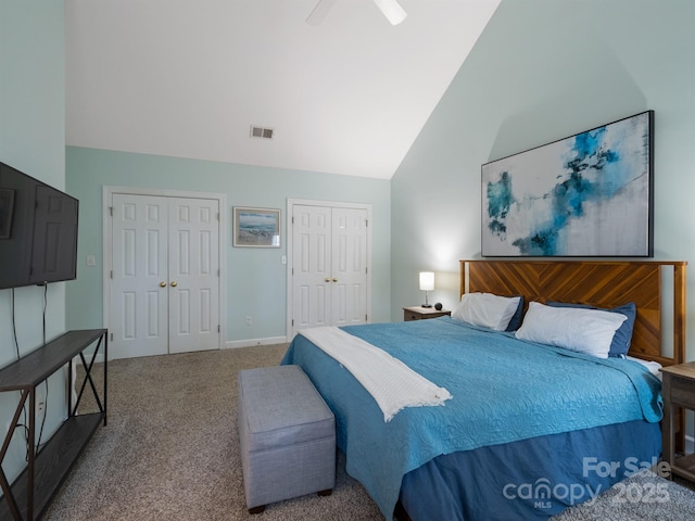 carpeted bedroom with lofted ceiling, two closets, and ceiling fan