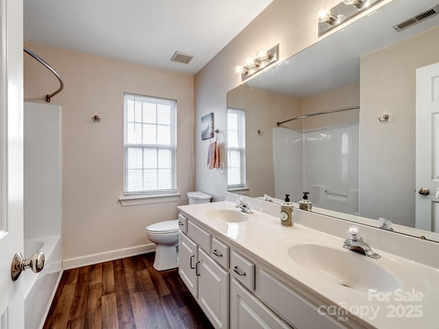 full bathroom with wood-type flooring, vanity, washtub / shower combination, and toilet