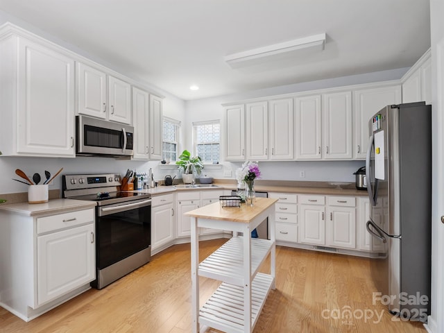 kitchen featuring white cabinetry, appliances with stainless steel finishes, and light hardwood / wood-style floors