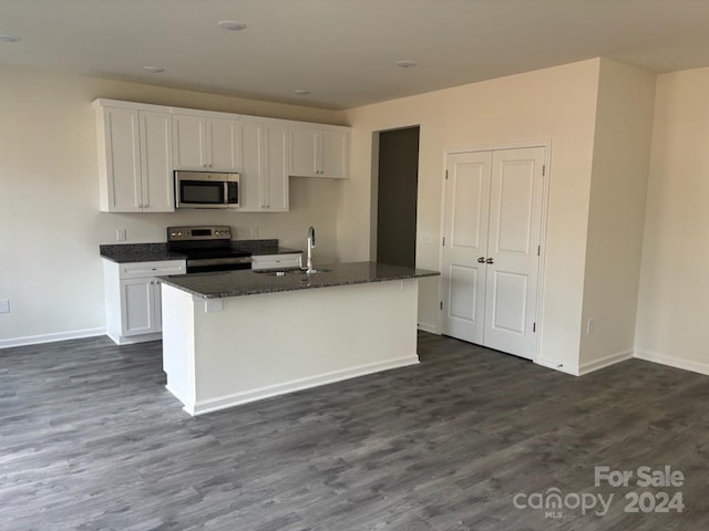 kitchen with stainless steel appliances, a kitchen island with sink, sink, white cabinets, and dark hardwood / wood-style floors