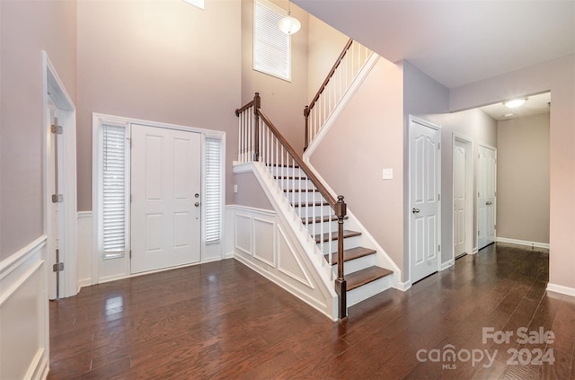 entrance foyer with dark hardwood / wood-style flooring and a towering ceiling