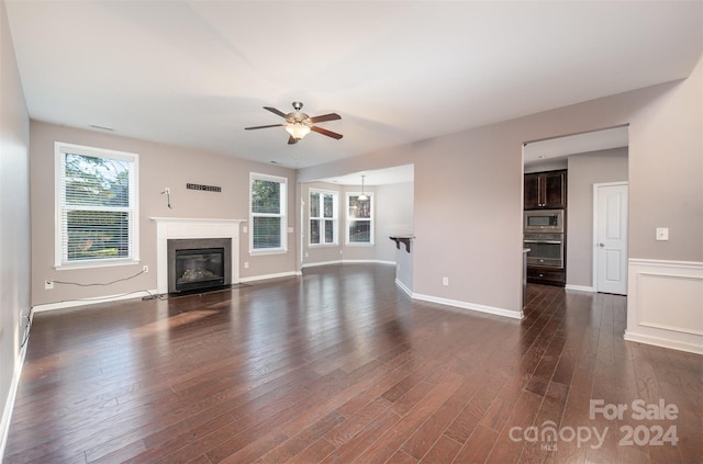 unfurnished living room with dark hardwood / wood-style flooring, a wealth of natural light, and ceiling fan