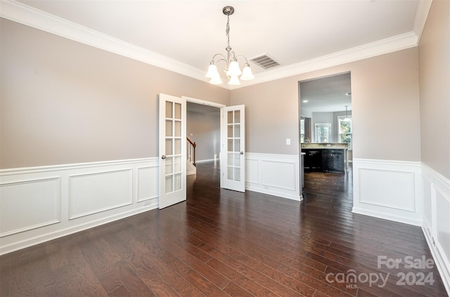 unfurnished dining area featuring french doors, an inviting chandelier, ornamental molding, and dark wood-type flooring