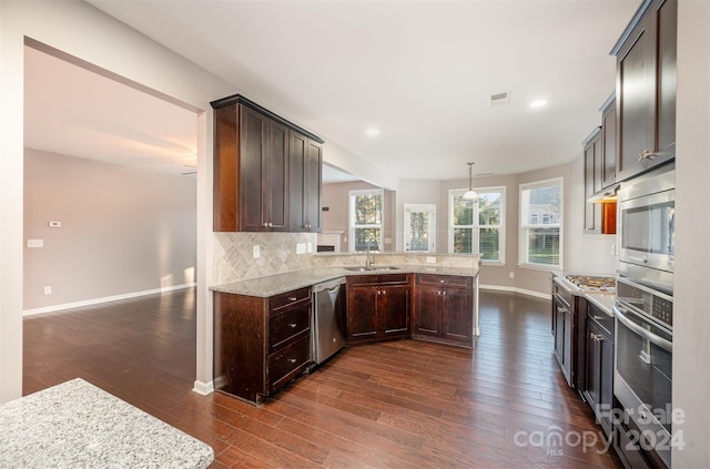 kitchen with kitchen peninsula, pendant lighting, dark hardwood / wood-style flooring, and appliances with stainless steel finishes