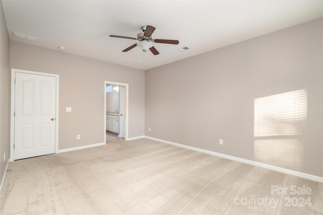 unfurnished bedroom with light carpet, connected bathroom, and ceiling fan