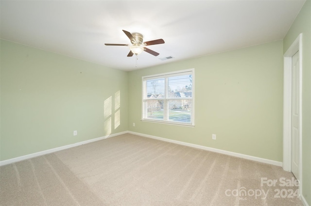 spare room featuring light colored carpet and ceiling fan