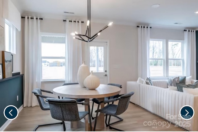 dining room with visible vents, light wood-style flooring, and an inviting chandelier