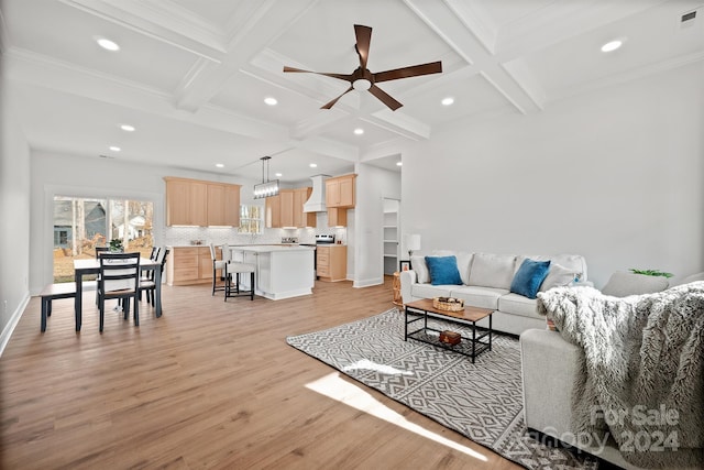 living room with light wood-type flooring, ornamental molding, coffered ceiling, ceiling fan, and beam ceiling