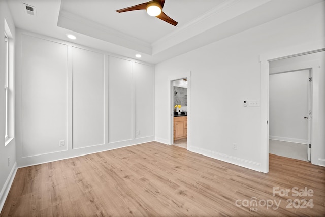 unfurnished room featuring light hardwood / wood-style floors, a raised ceiling, and crown molding