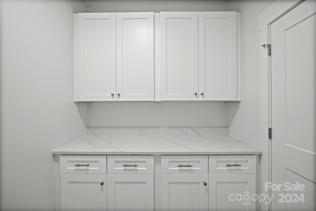 interior space featuring light stone countertops and white cabinetry