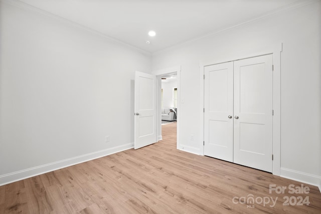 unfurnished bedroom with light wood-type flooring, ornamental molding, and a closet