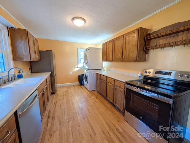 kitchen with stacked washer and clothes dryer, sink, light hardwood / wood-style flooring, ornamental molding, and appliances with stainless steel finishes