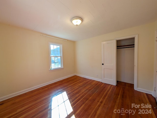 unfurnished bedroom with a closet and dark wood-type flooring