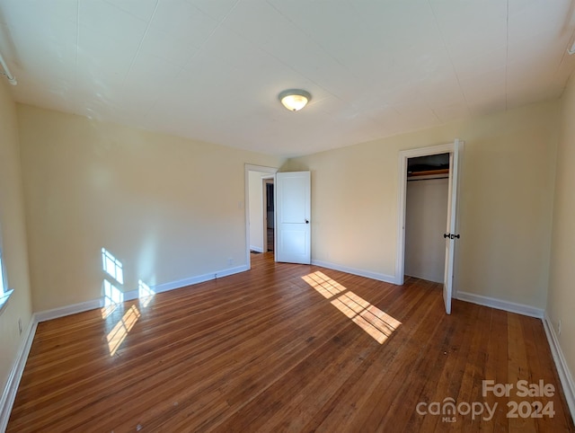 unfurnished bedroom featuring a closet and dark wood-type flooring