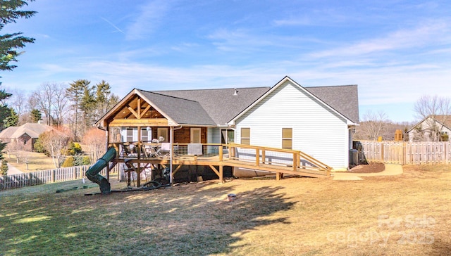 back of property with a wooden deck, a yard, and a playground