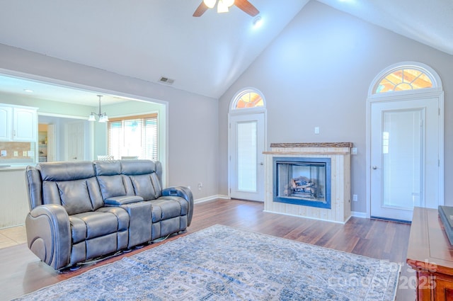 living room featuring ceiling fan with notable chandelier, hardwood / wood-style floors, and high vaulted ceiling