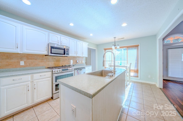 kitchen featuring decorative light fixtures, sink, white cabinets, a kitchen island with sink, and stainless steel appliances