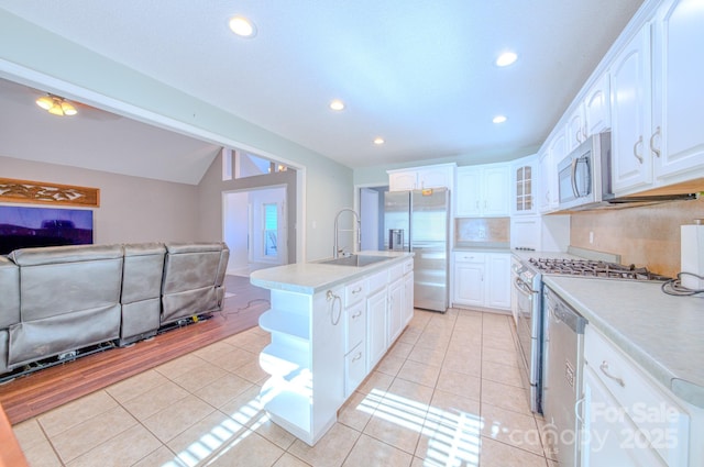 kitchen featuring sink, light tile patterned floors, appliances with stainless steel finishes, a kitchen island with sink, and white cabinets