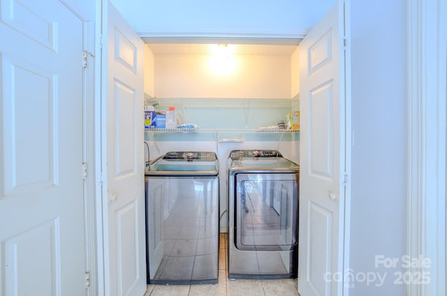 laundry area with washing machine and clothes dryer and light tile patterned floors