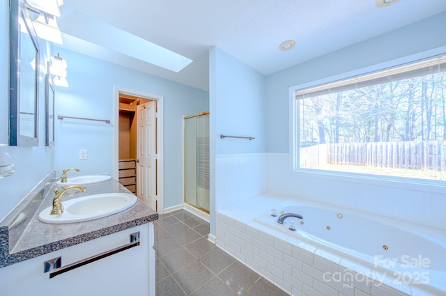 bathroom with vanity, shower with separate bathtub, a skylight, and tile patterned flooring