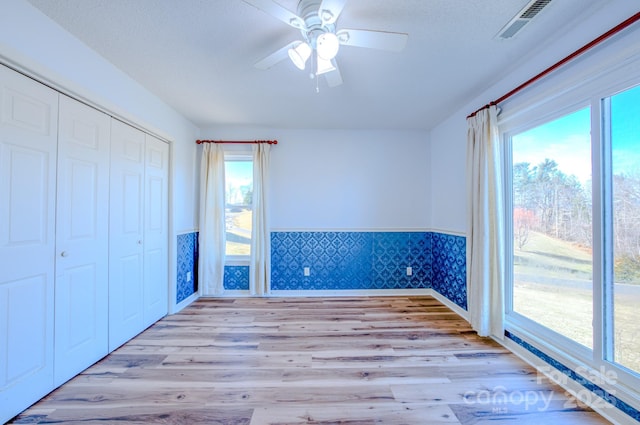 unfurnished bedroom with ceiling fan, light wood-type flooring, and a closet