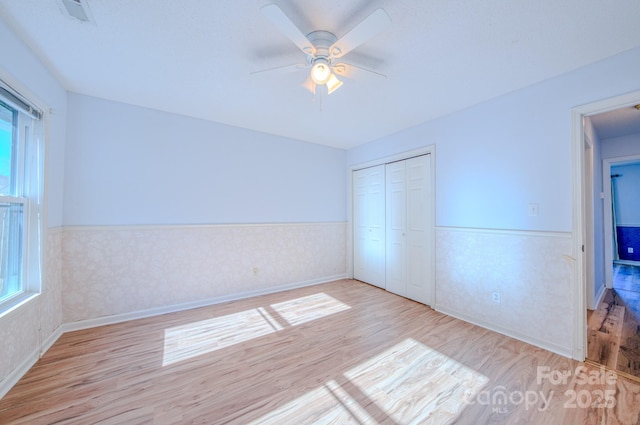 unfurnished bedroom with ceiling fan, light hardwood / wood-style floors, and a closet