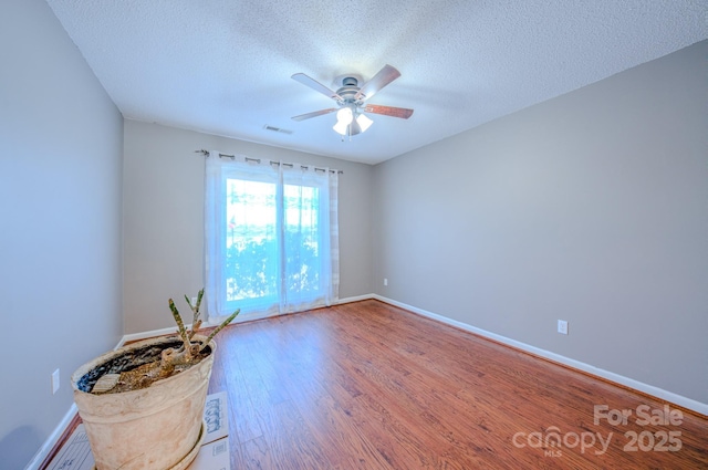 spare room featuring a textured ceiling, wood-type flooring, and ceiling fan