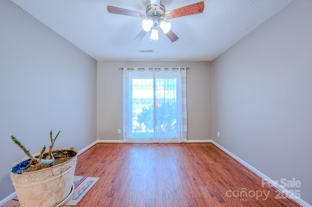 spare room with hardwood / wood-style flooring, ceiling fan, and a textured ceiling