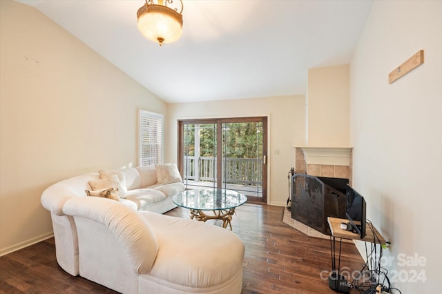 living room with a tiled fireplace, dark wood-type flooring, and vaulted ceiling