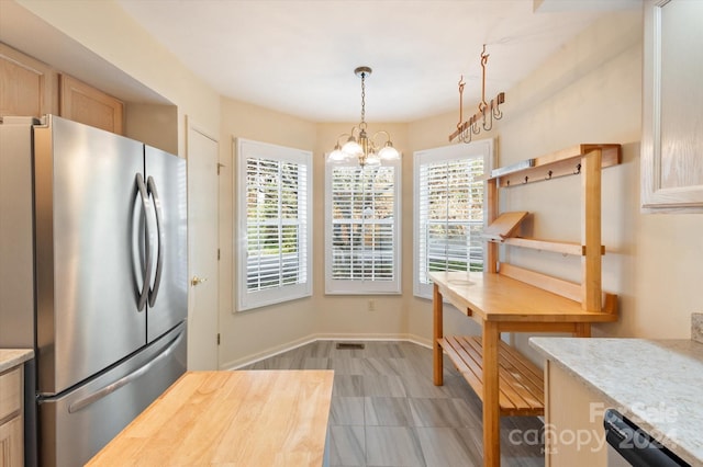 kitchen with pendant lighting, plenty of natural light, stainless steel fridge, and an inviting chandelier