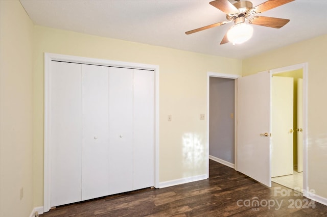 unfurnished bedroom with dark hardwood / wood-style flooring, a closet, and ceiling fan