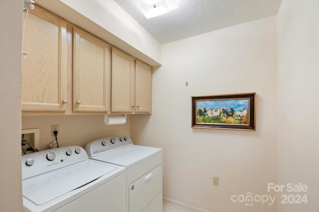 clothes washing area featuring washer and dryer, cabinets, and a textured ceiling