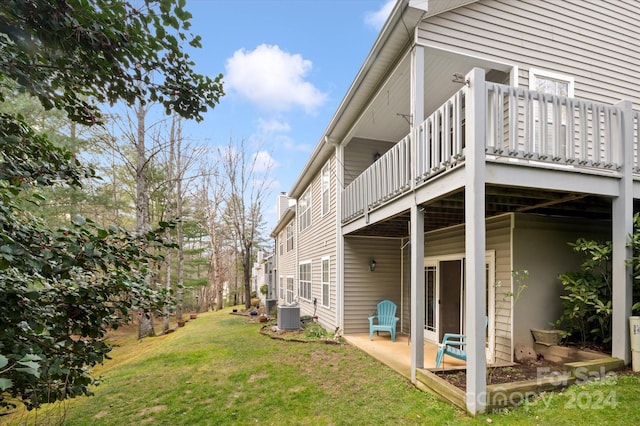 view of side of property featuring a patio area, a yard, a wooden deck, and central AC unit