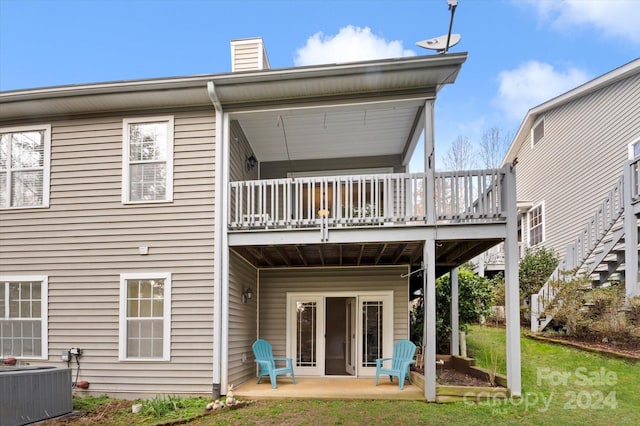 rear view of house featuring a lawn, cooling unit, and a patio