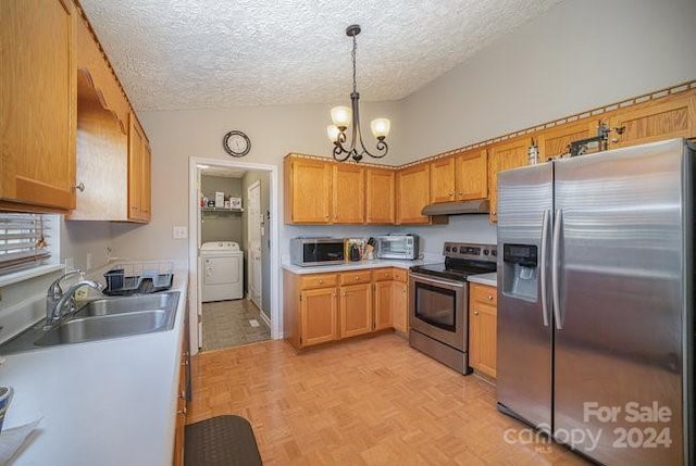 kitchen with stainless steel appliances, vaulted ceiling, sink, washer / dryer, and hanging light fixtures