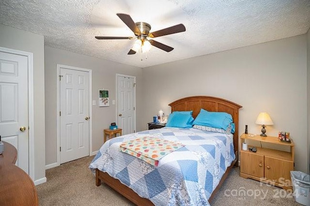 carpeted bedroom featuring ceiling fan and a textured ceiling