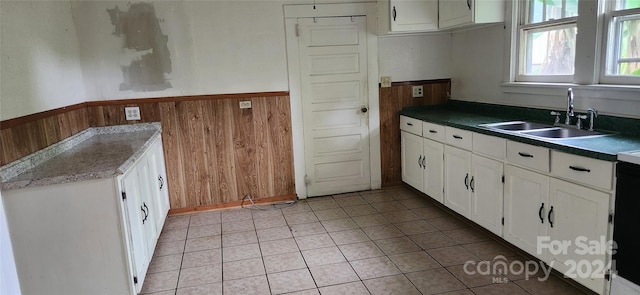 kitchen featuring wood walls, white cabinetry, and sink