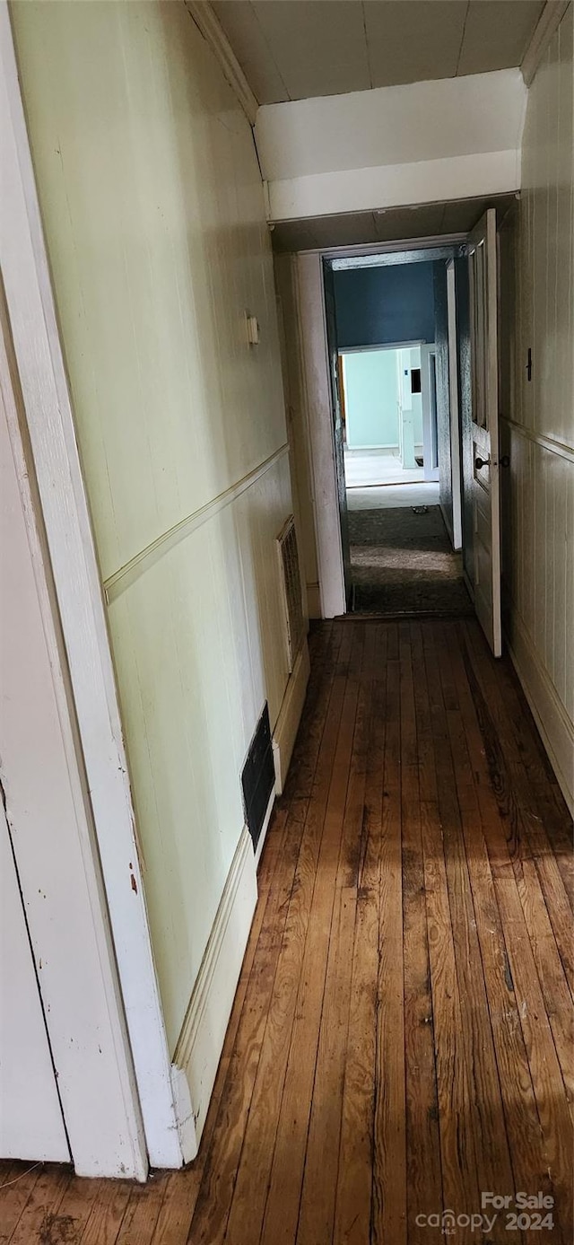 hallway featuring dark wood-type flooring and wooden walls