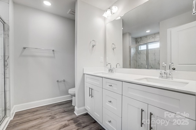 bathroom with hardwood / wood-style floors, a shower with door, toilet, and vanity