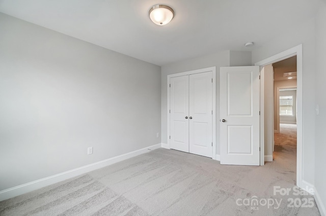 unfurnished bedroom featuring light carpet and a closet