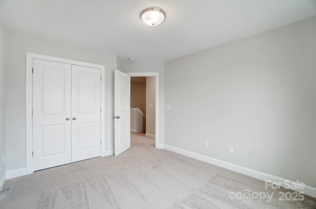 unfurnished bedroom with light colored carpet and a closet