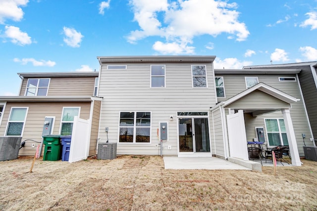 back of property with central air condition unit, a lawn, and a patio