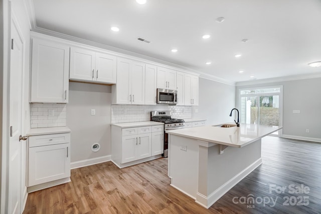 kitchen with sink, stainless steel appliances, white cabinetry, and a center island with sink