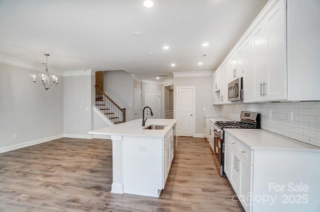 kitchen featuring sink, stainless steel appliances, white cabinetry, and an island with sink