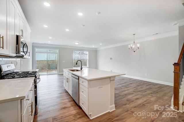 kitchen featuring white cabinets, stainless steel appliances, and an island with sink